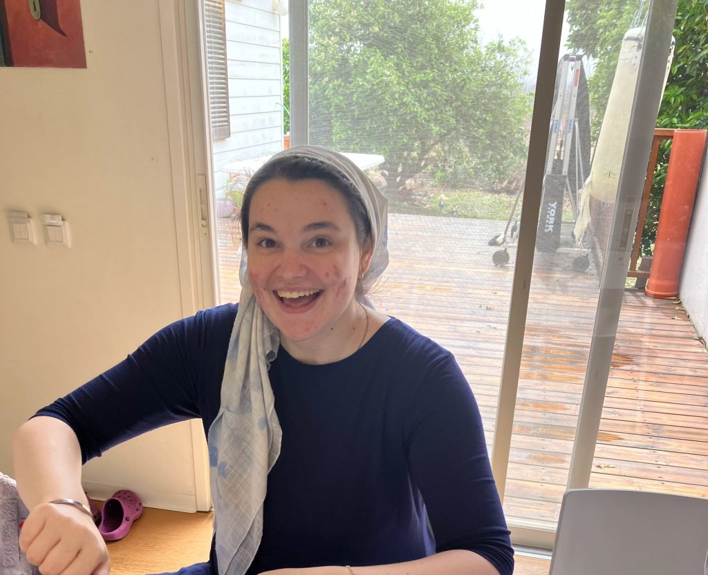Leora sitting peeling vegetables with a big smile on her face